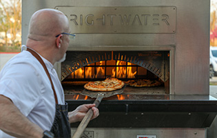 Man pulling a pizza out of a pizza oven