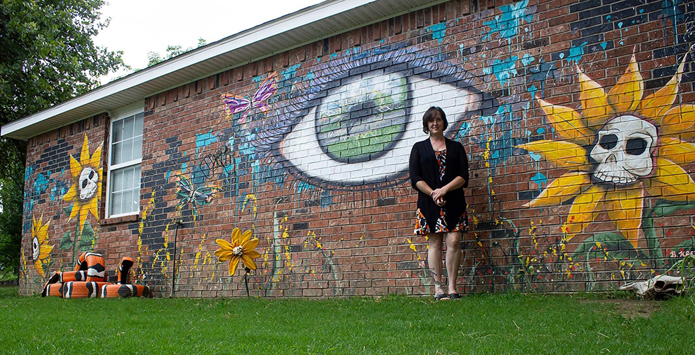 Becky in front of large mural she has painted