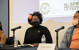 Speaker Sitting at Table in Front of a Microphone