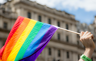 A Hand Holding a LGBTQ+ Flag