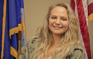 Female veteran smiling in front of flags